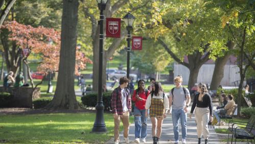 a group of five students walking and chatting with each other